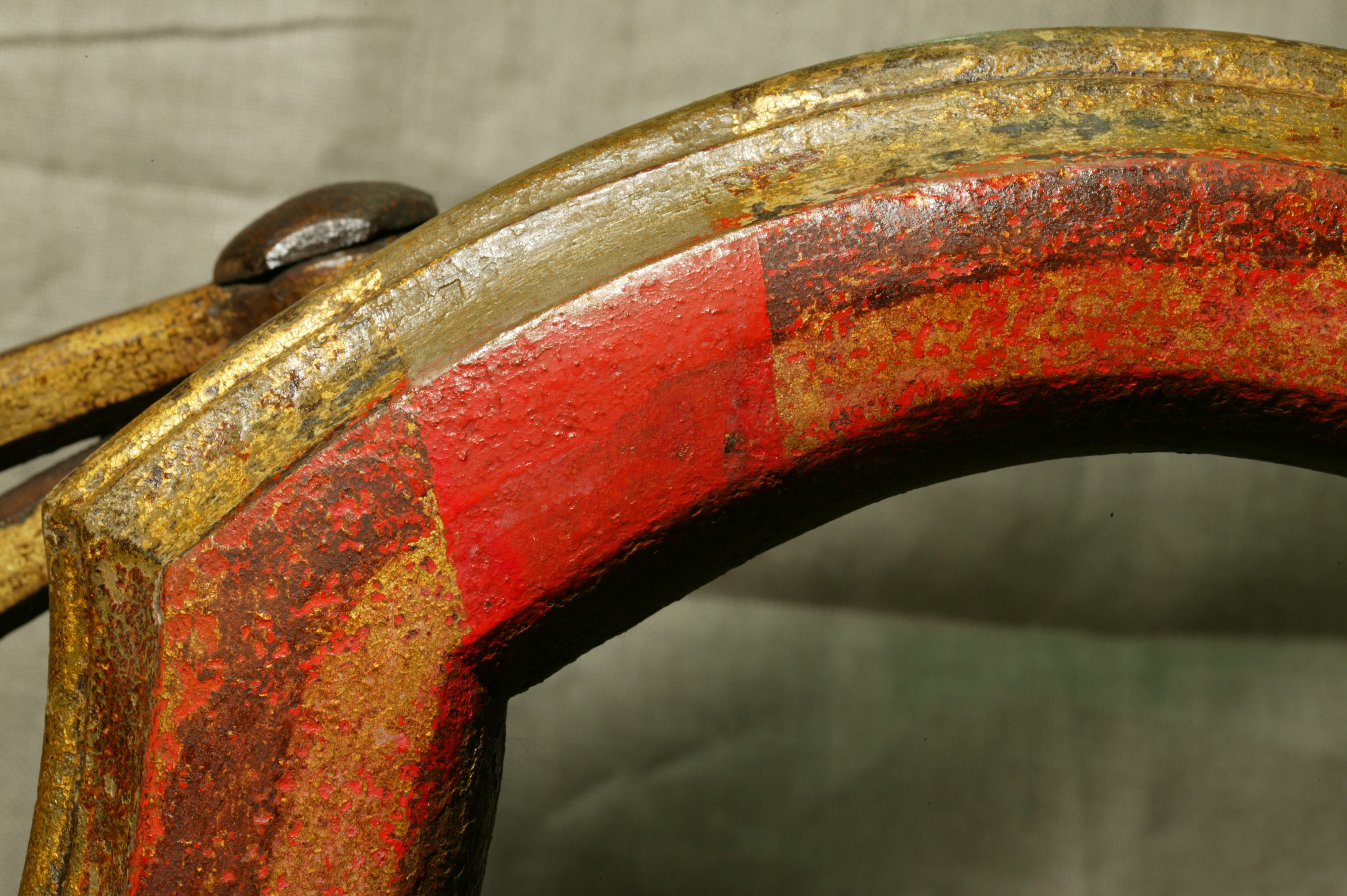 Фрагмент металлической дрожины кареты после реставрации: раскрыта авторская позолота и красочный слой, оставлен фрагмент с поздними «записями». 2009 
