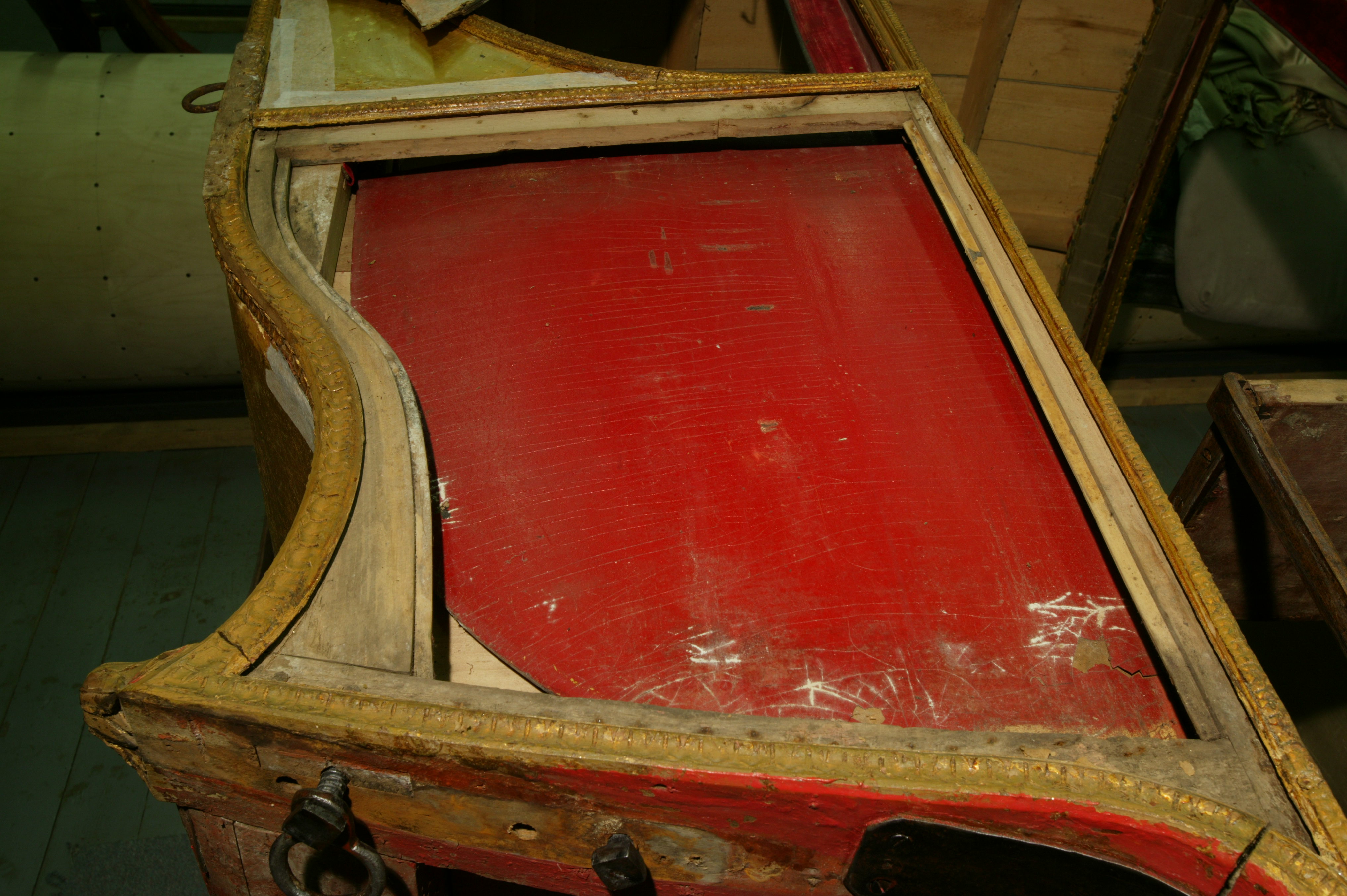 Фрагмент кузова кареты. Левая боковая филенка (стенка кузова) демонтирована, внутри – красная «шторка», которая может подниматься наверх, закрывая боковое стекло в салоне кареты. До реставрации. 2008 